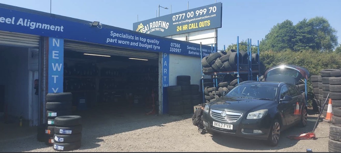 A2Z Tyre Recycling yard with racks of part worn tyres and a car being repaired