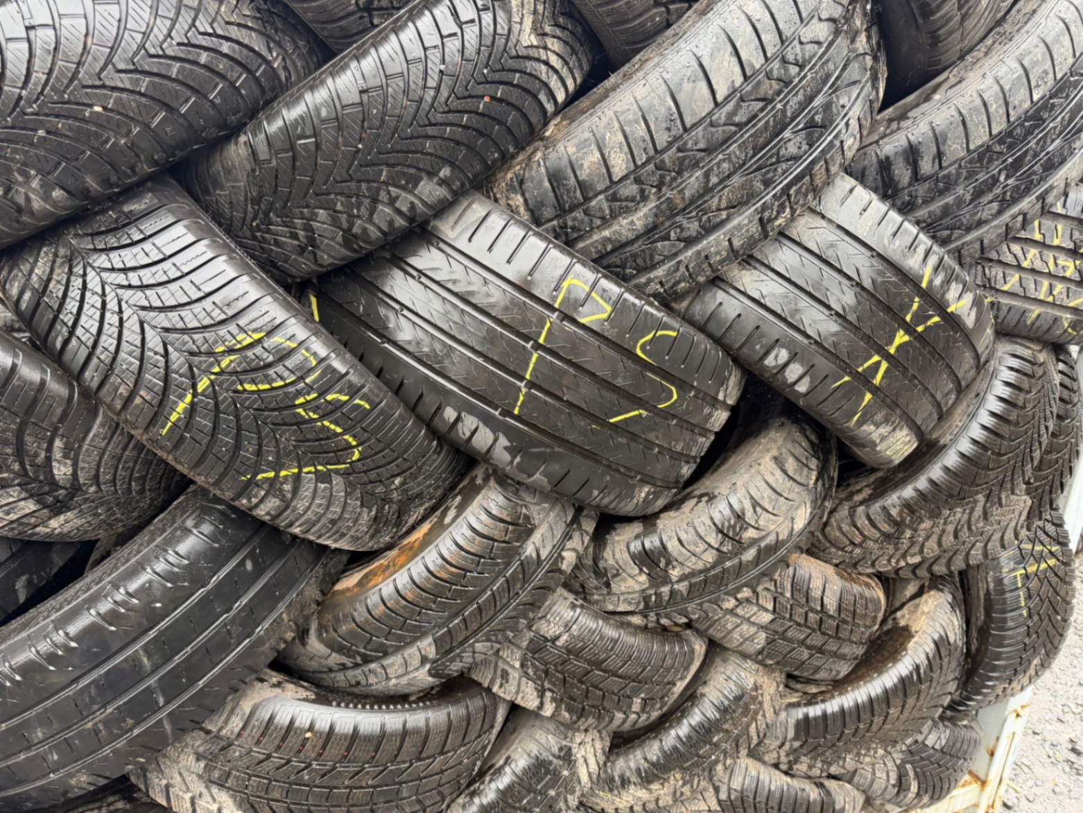Close-up of used tyres stacked and marked for grading